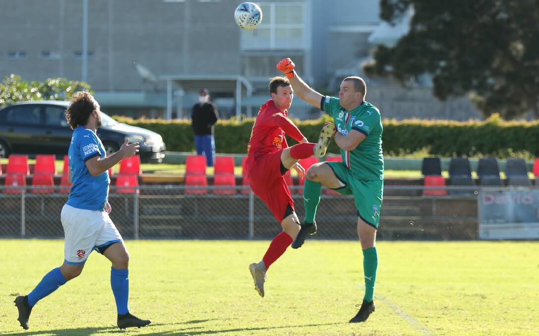HIGH ACHIEVER: Charlestown Azzurri goalkeeper Nathan Archbold punches clear a ball under pressure from Broadmeadow's Jon Griffiths this season. Picture: Max Mason-Hubers