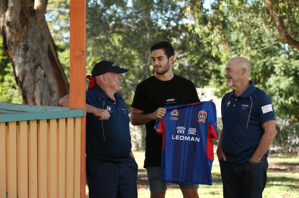 GIFT: Cameron Holzheimer receiving a signed Newcastle Jets jersey from Ross Gray and Bill Pryce from Men of Football, Hunter. Picture: Simone De Peak