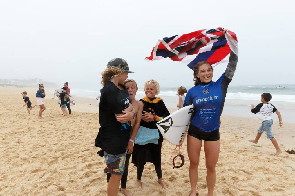 SWEET VICTORY: Coco Ho waves the Hawaiian flag after her win in the Surfest women's final on a rainy Sunday afternoon at Merewether Beach. Picture: Max Mason-Hubers