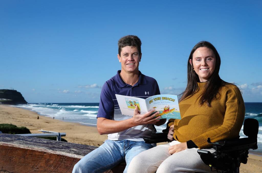 A GOOD READ: Author Boyd Conrick and Jess Collins with a copy of 'At the Beach with Lizzie and Luke - Shark Sighting' on Wednesday at Merewether Beach. Picture: Marina Neil