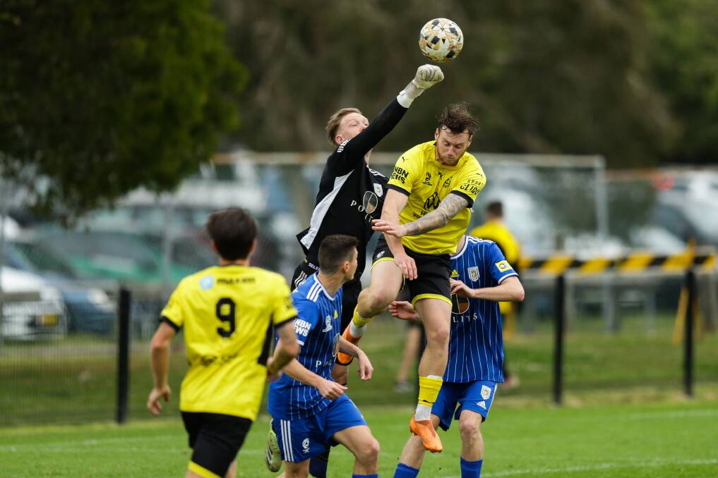 Olympic keeper Adam Pearce punches clear the ball under pressure from Lambton's Ben Hay on Sunday at Edden Oval. Picture by Jonathan Carroll