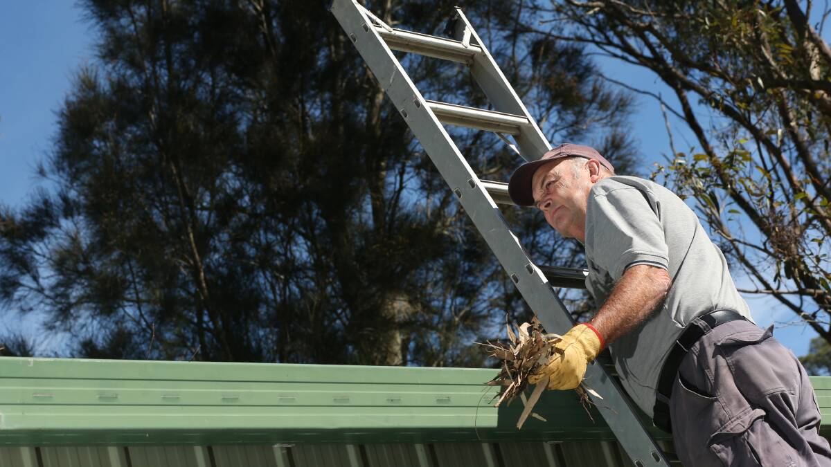 TIDY: Dave Fairless clearing leaves from his gutter as he prepares his property for the upcoming bushfire danger period. Picture: Simone De Peak