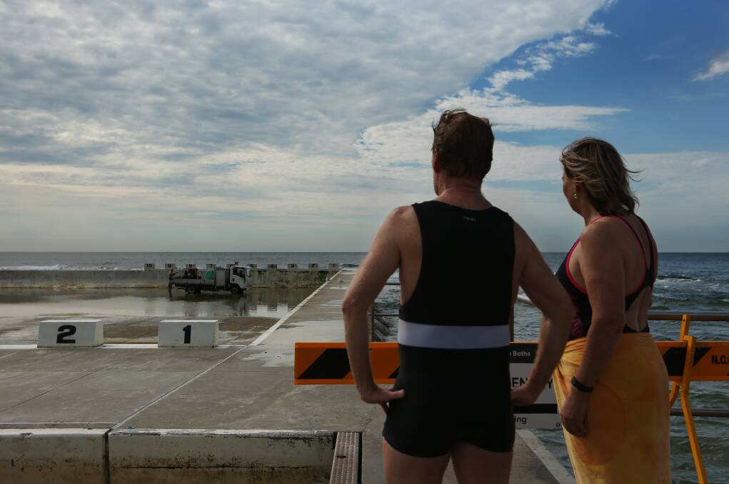 ISSUES: Regular baths swimmers Steven Fleming and councillor Kath Elliott watch on as Merewether Ocean Baths is cleaned. Picture: Simone De Peak
