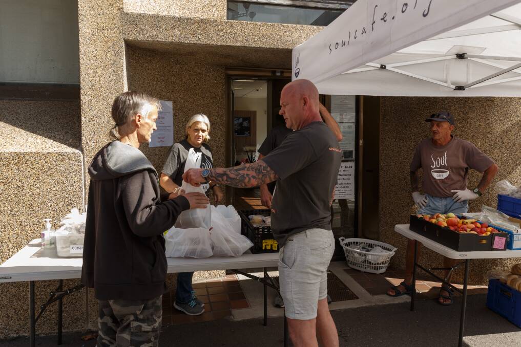 Still helping: Soul Cafe volunteer David Dorhauer passes a bag with pre-packed meals to a man at their outdoor soup kitchen. Picture: Max Mason-Hubers