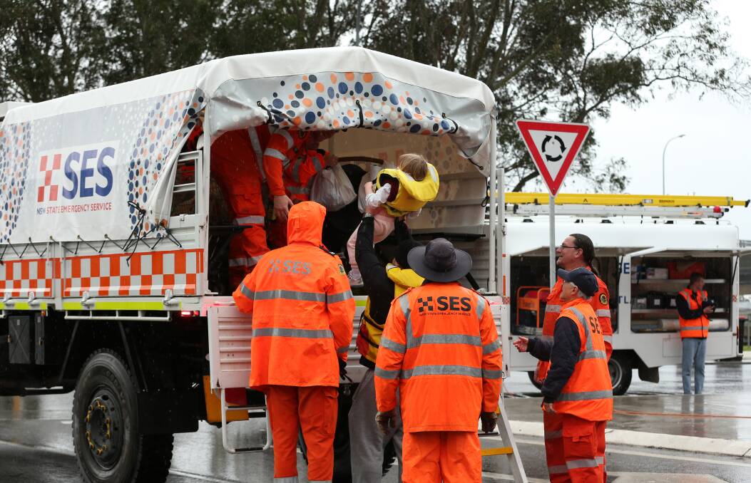 STANDING UNITED: Gillieston Heights residents pictured on Tuesday boarding an SES truck to be transported back to their homes. PICTURE: SImone De Peak.
