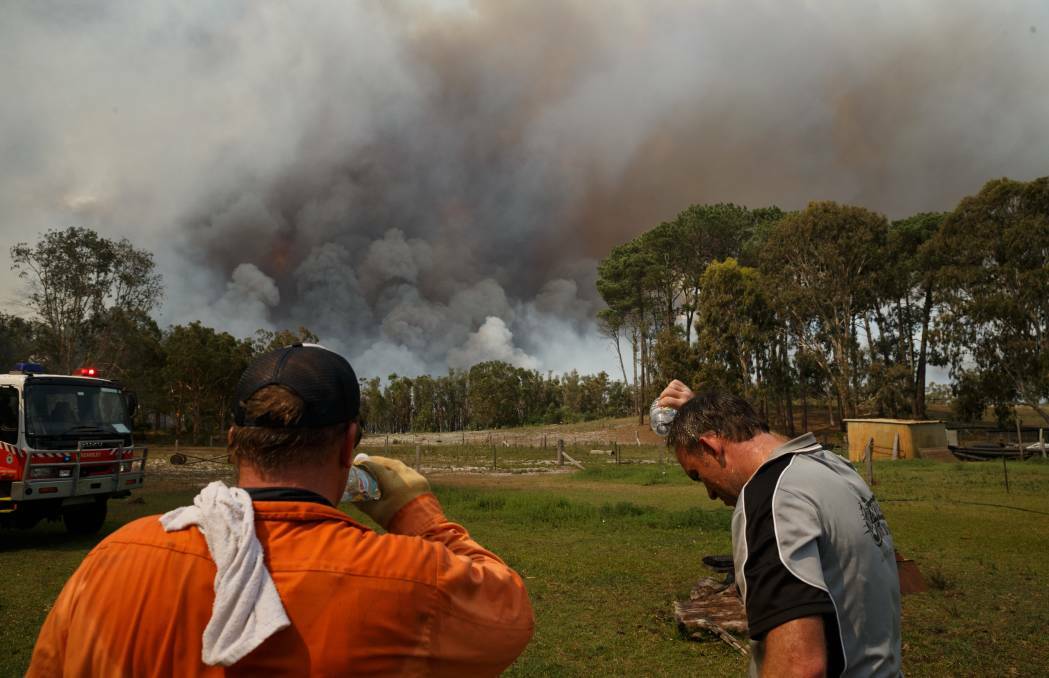 Cain Gorfine, right, waits for the fire front to approach his Cabbage Tree Road property on Saturday afternoon. Picture: Max Mason-Hubers 