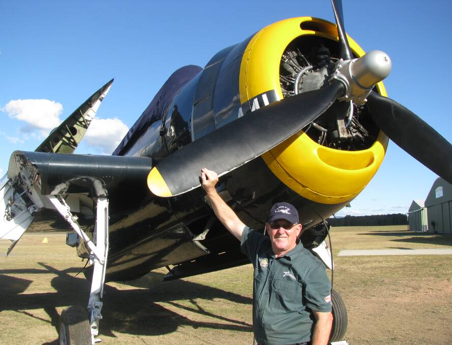 AND THEIR FLYING MACHINE: Benson with the museum's yellow-tipped 1942 Grumann Avenger torpedo bomber (with folded wings).