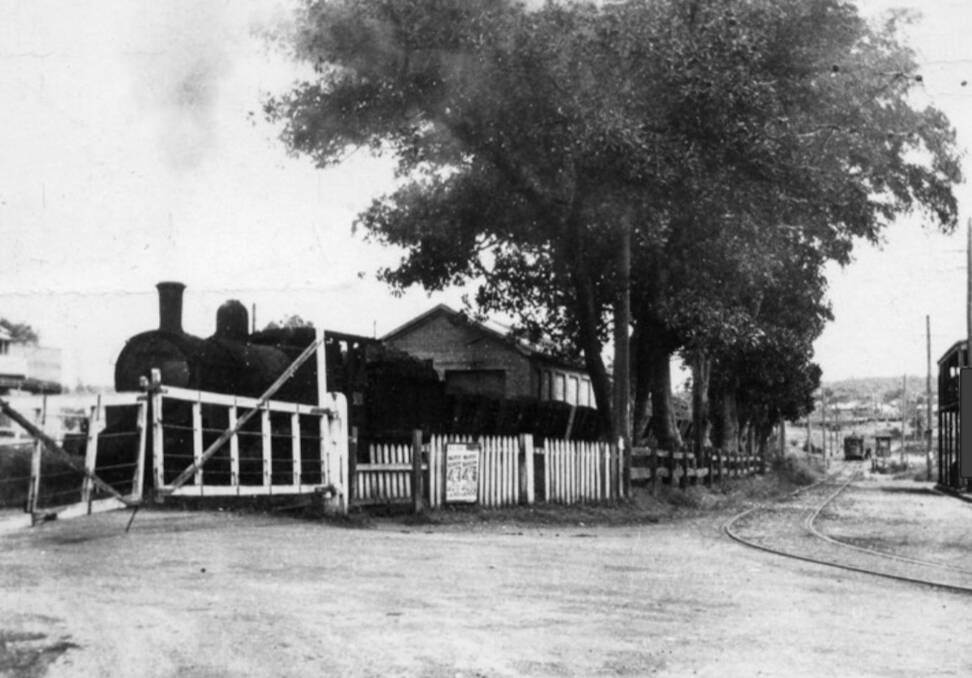 All aboard: A steam train chugs past Wallsend's goods shed. At right, a tram is visible on a parallel track past the Fig Tree Hotel.