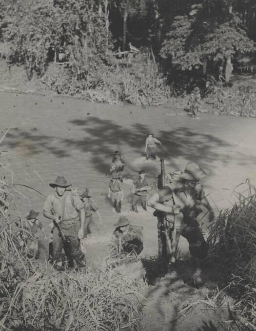 DRIVING ON: An Australian patrol crosses a jungle river in New Guinea, April 1945. Picture: University of Newcastle's Cultural Collections.