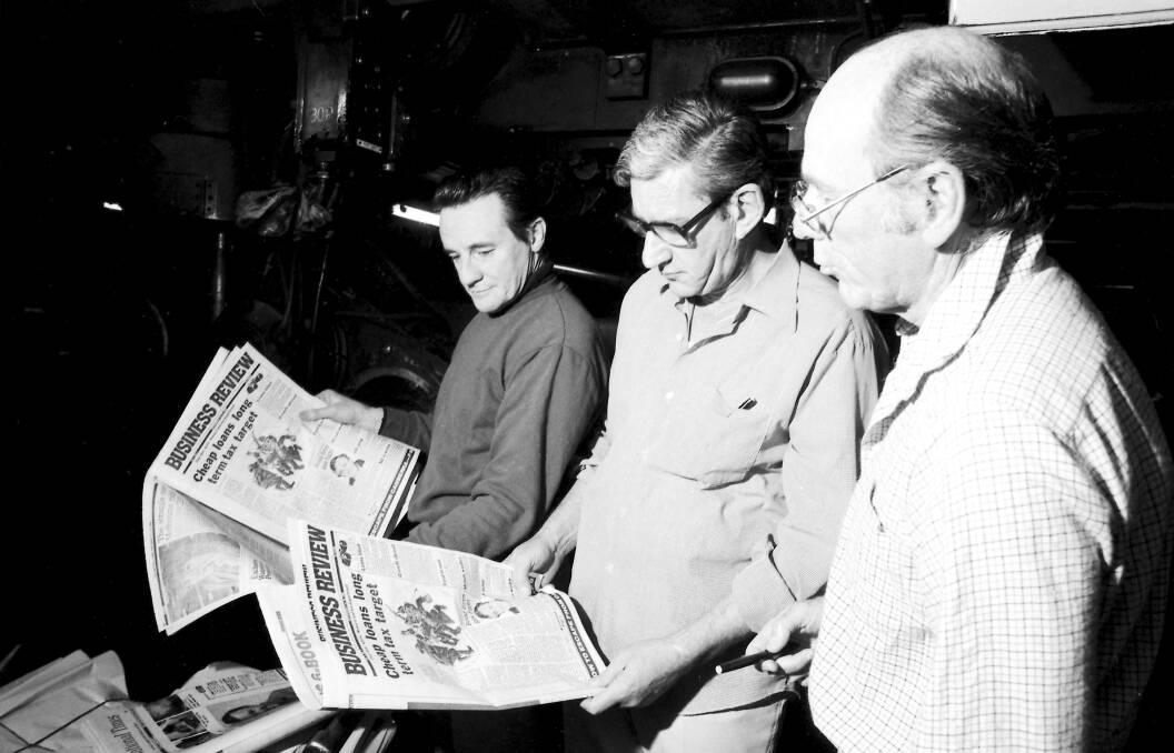 KEEN EYE: Evan Whitton, centre, inspecting an issue hot off the presses,