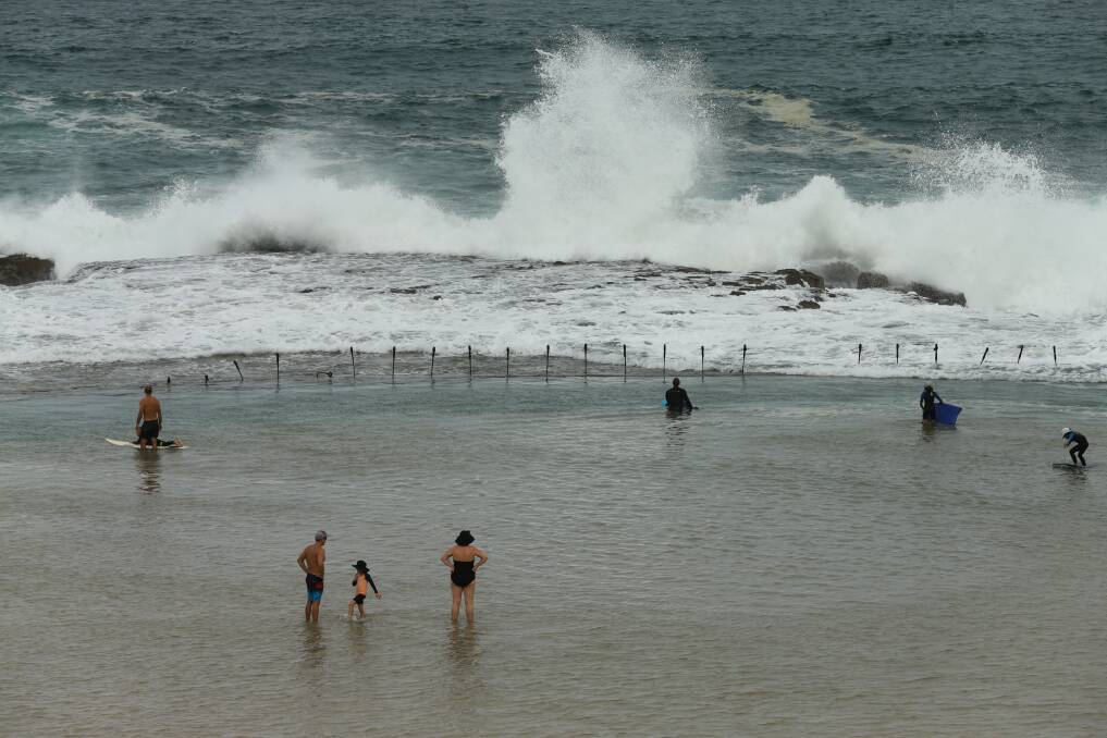 TAKING A DIP: Swimmers keep their distance in the Canoe Pool next to Newcastle Ocean Baths on Monday. Picture: Jonathan Carroll