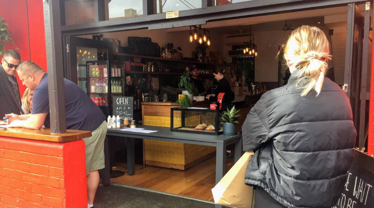 CAREFUL: A takeaway customer waits outside Three Monkeys in Darby Street. The cafe is recording the contact details of people who choose to sit down. 
