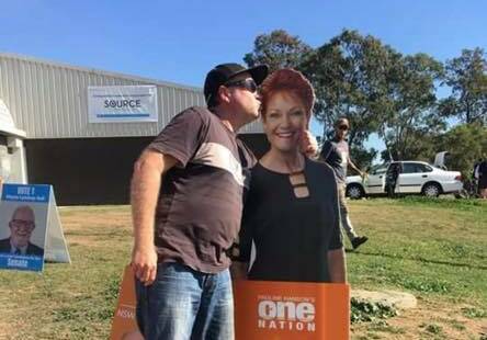 A man plants a kiss on a Pauline Hanson cut-out on election day.