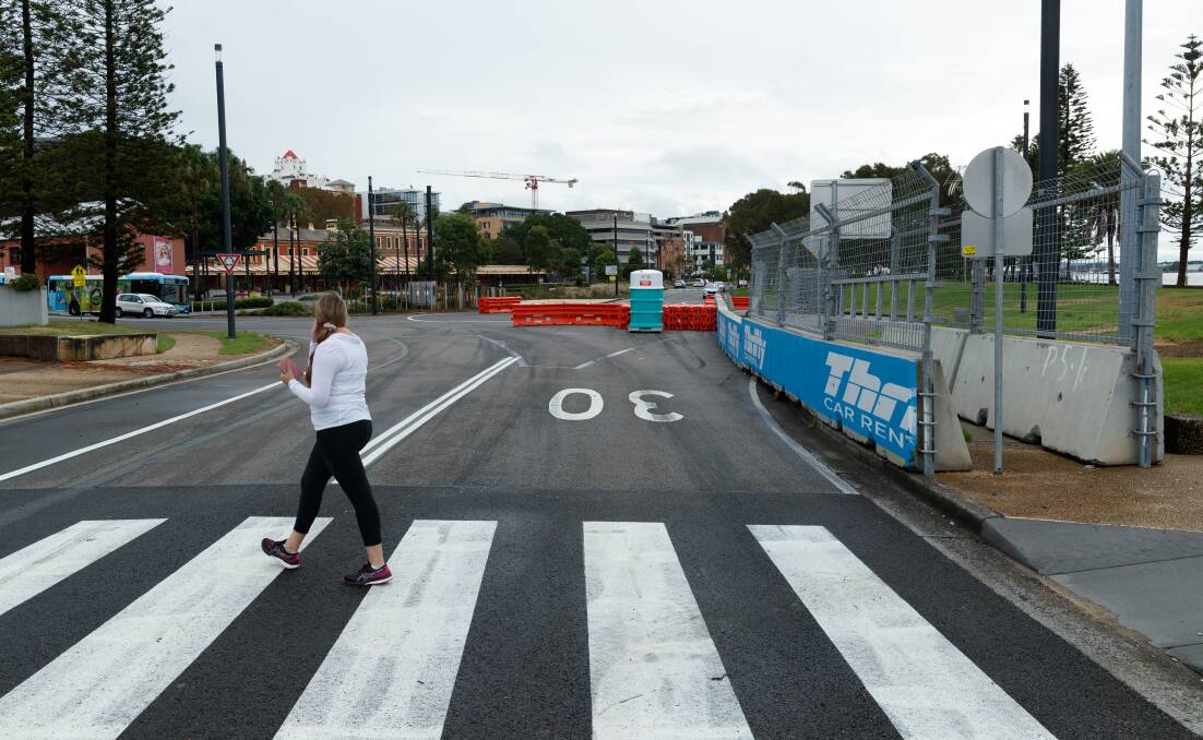 A woman walks on a makeshift pedestrian crossing in Wharf Road as workers pack up after the 2023 Supercars race. File picture