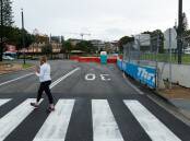 A woman walks on a makeshift pedestrian crossing in Wharf Road as workers pack up after the 2023 Supercars race. File picture