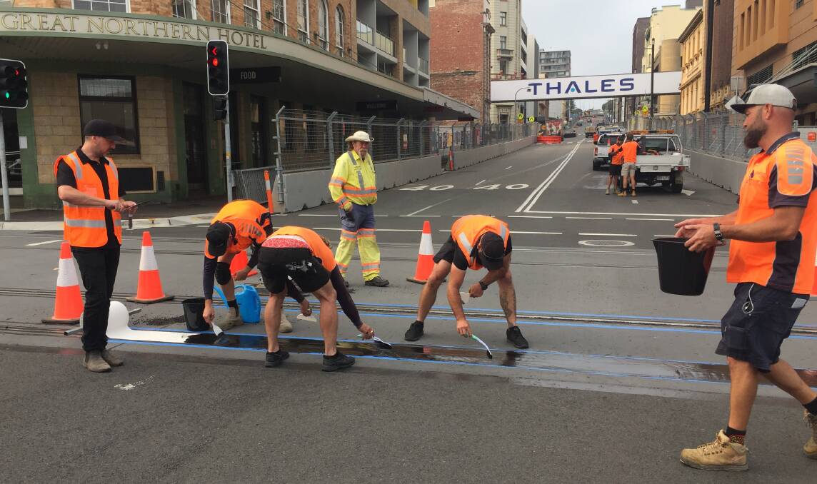 FINISHING TOUCHES: Workers cover up the light rail tracks in Scott Street on Thursday. 