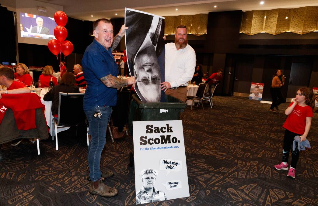 DUMPED: Dan Repacholi and a Labor supporter dispose of a Scott Morrison poster on Saturday night at Cessnock Leagues Club.