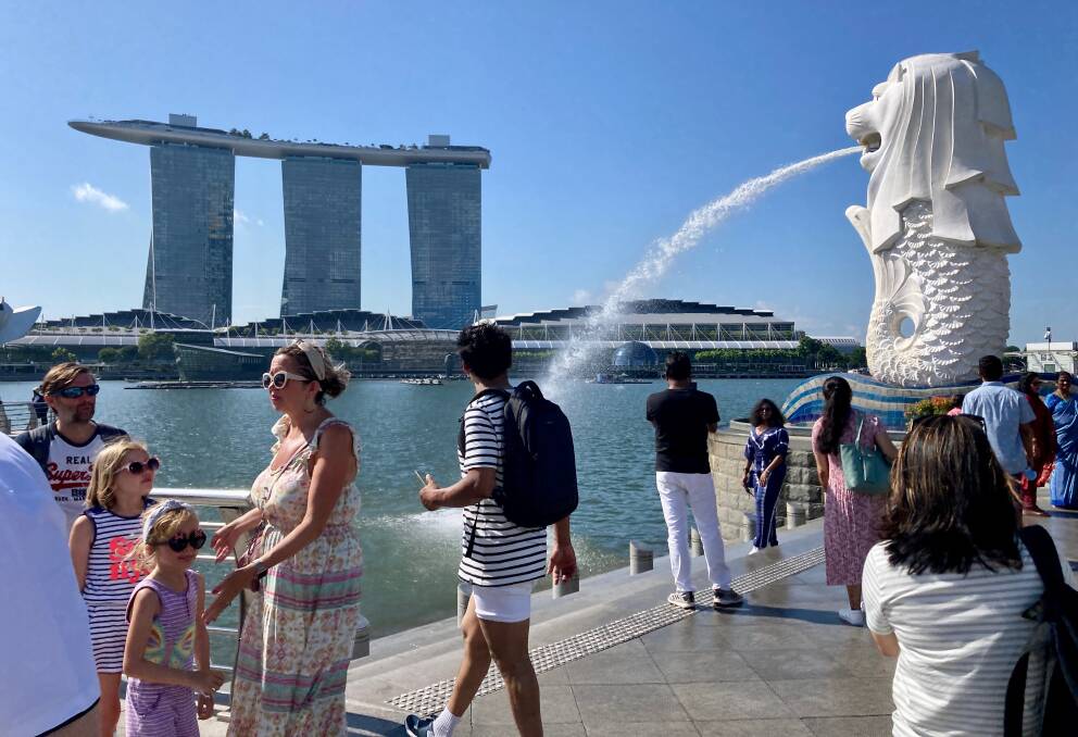 Tourists look across Marina Bay to the precinct's huge hotel and shopping complex. 