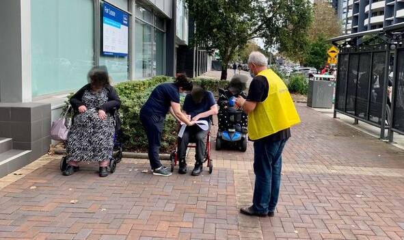 'UNACCEPTABLE': People in wheelchairs voting on the footpath outside the Newcastle pre-poll centre in King Street on Monday. Picture: Sharon Claydon/Twitter