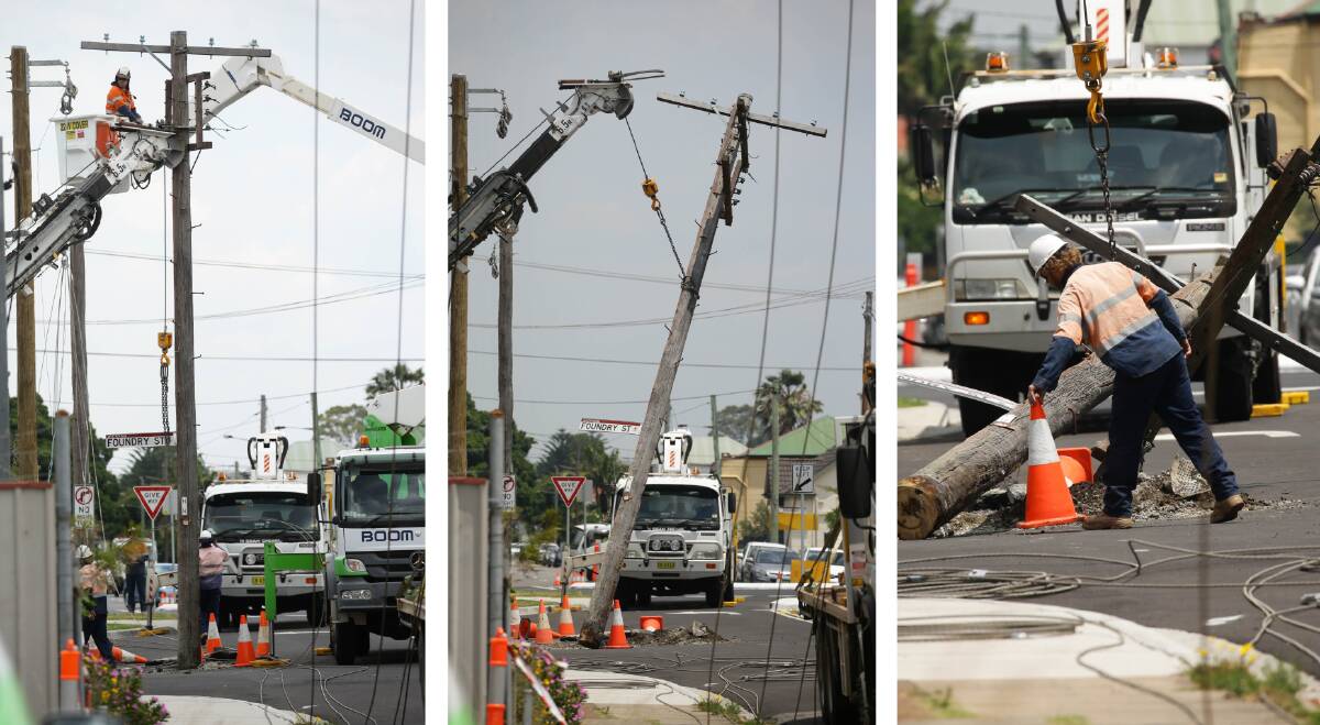DOWN AND OUT: Contractors remove the power pole from the street in Wickham. Pictures: Jonathan Carroll 