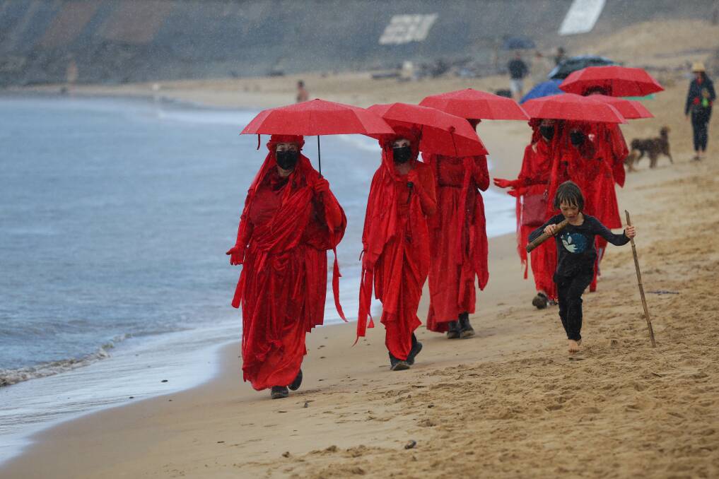 RED ALERT: Extinction Rebellion protesters walk along the beach on Sunday.