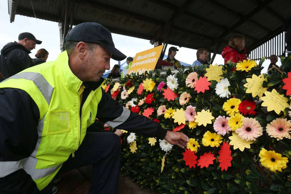 Peter Robert from Hunter Water puts a tribute on the commemorative flower wall.