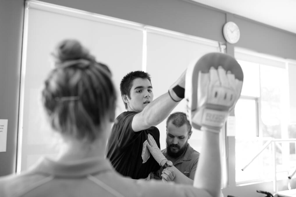 Road to recovery: Physiotherapist Aidan Vassallo supports Lawson Rankin while he goes through a boxing routine with fourth year UoN physio student Julia Barton at the Rankin Park Centre gym. Picture: Max Mason-Hubers