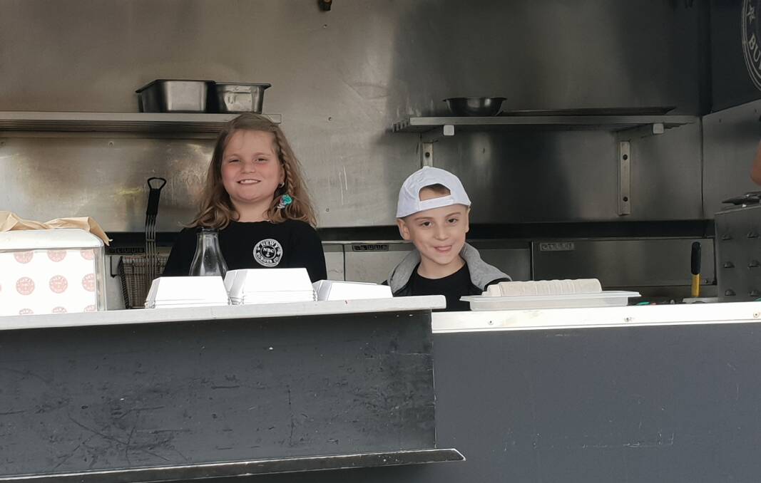 Feeding the troops: Ashtonfield siblings Naveen and Kane Ransom in the Newy Burger Co food truck at the Build For A Cure site at Medowie. Kane, 7, is receiving treatment for leukaemia for the second time. He was first diagnosed when he was 3 years old.