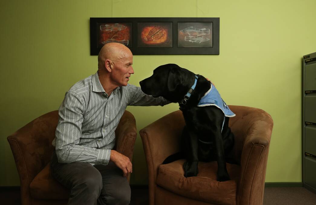 Passive presence: Black labrador Nelson, with clinical Psychologist Dr Paul Spencer, offers animal assistance therapy for children and adults with PTSD and depression. Picture: Simone De Peak.