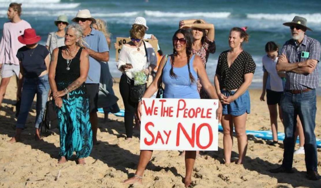 A protester holds a sign at an anti-PEP-11 rally at Bar Beach in February 2022.