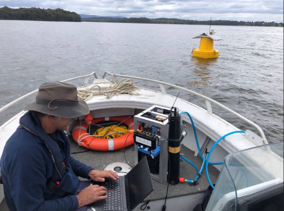 An research officer reads data from a smart buoy that was deployed off Wyee Point following the second fish kill. Picture supplied. 