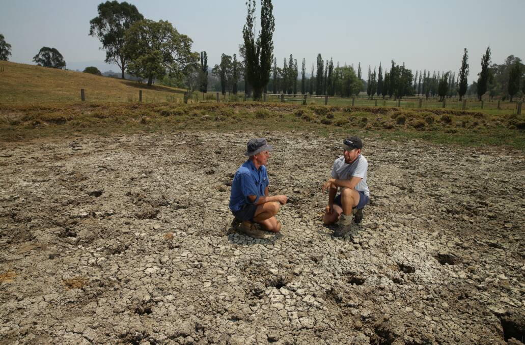 Searching for answers: Chris and James McRae walking through one of 12 dried out watering holes on their dairy farm. Picture: Jonathan Carroll