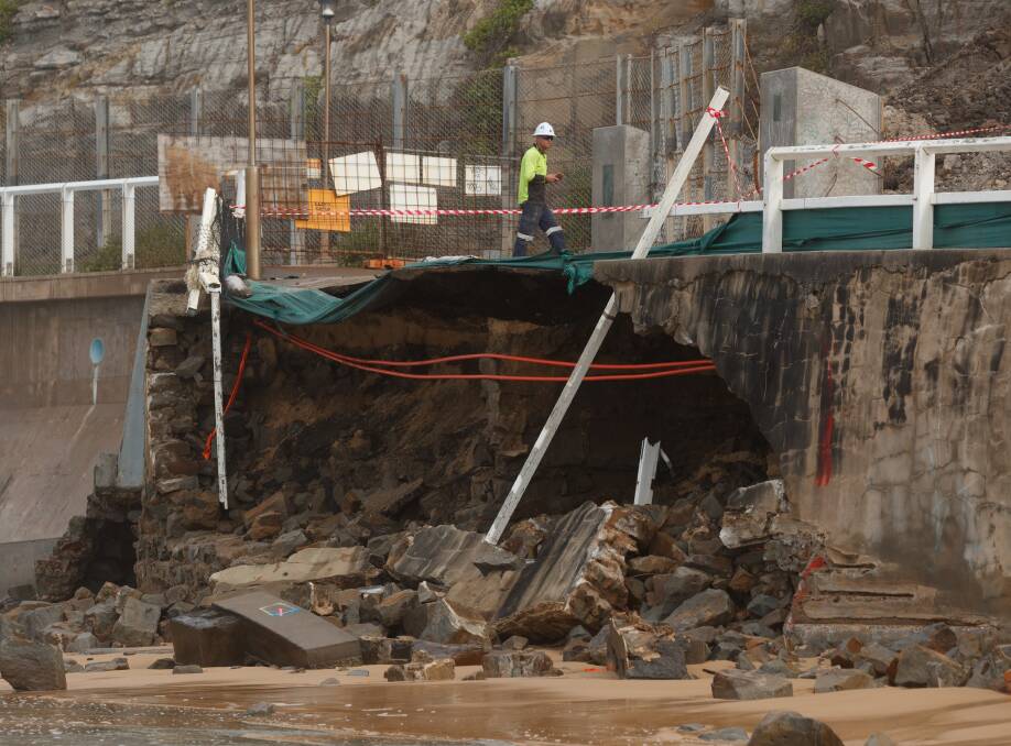 Tricky job: Workers inspect the collapsed section of sea wall on Monday. Picture: Max Mason Hubers. 