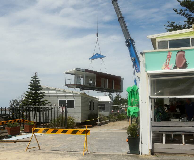 Up and away: The first holiday cabin is lifted out of harm's way on Tuesday. Picture: Jonathan Carroll