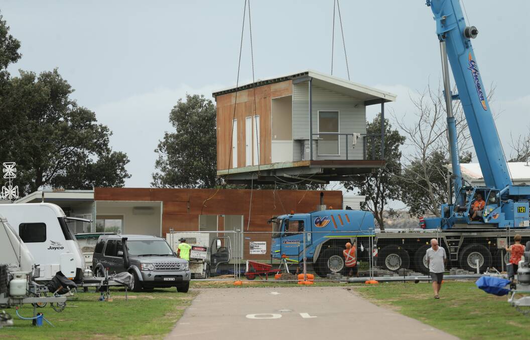 On the move: Another section of a holiday cabin is lifted away from the heavily eroded foreshore at Stockton Caravan Park on Wednesday. Picture: Jonathan Carroll