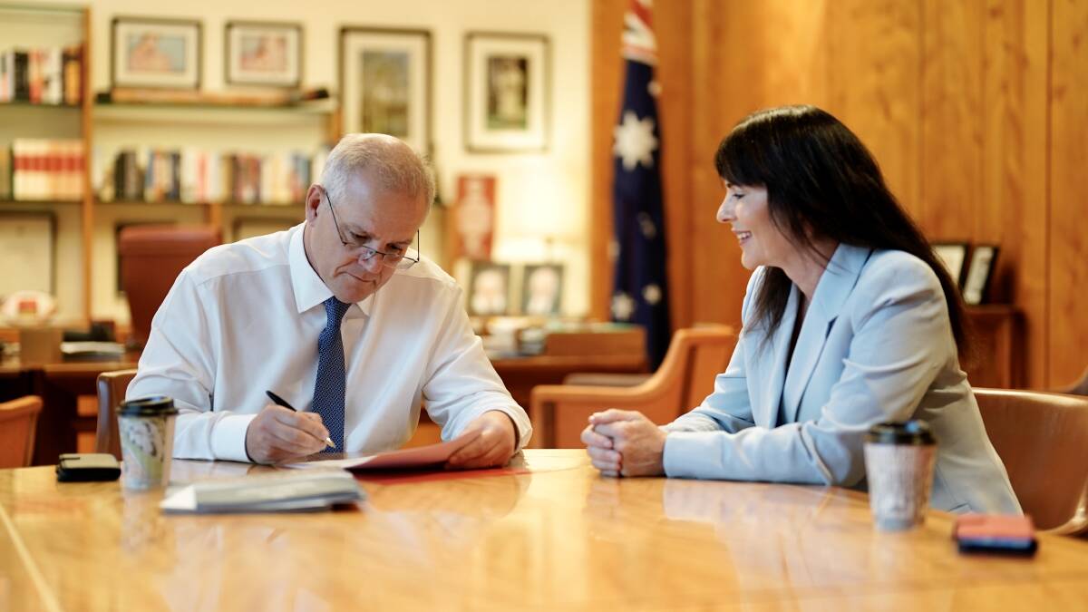 Prime Minister Scott Morrison signs the government's refusal of the PEP-11 application on Thursday as Robertson MP Lucy Wicks looks on. 