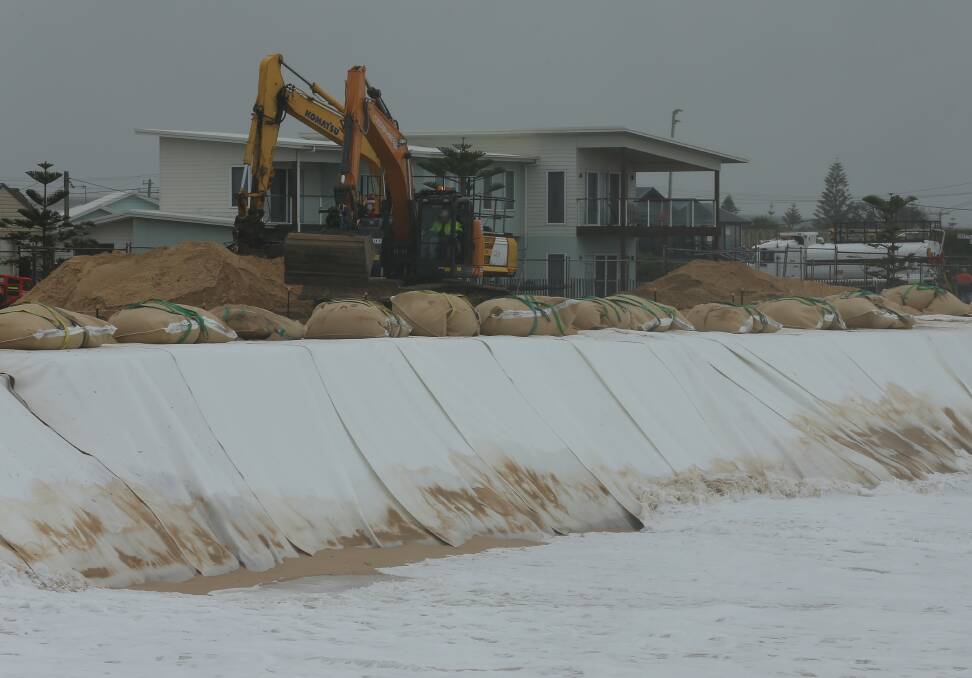 Around the clock: Contractors worked across the weekend to secure the suburb with sandbags. More large swell is expected on Tuesday. Picture: Simone DePeak