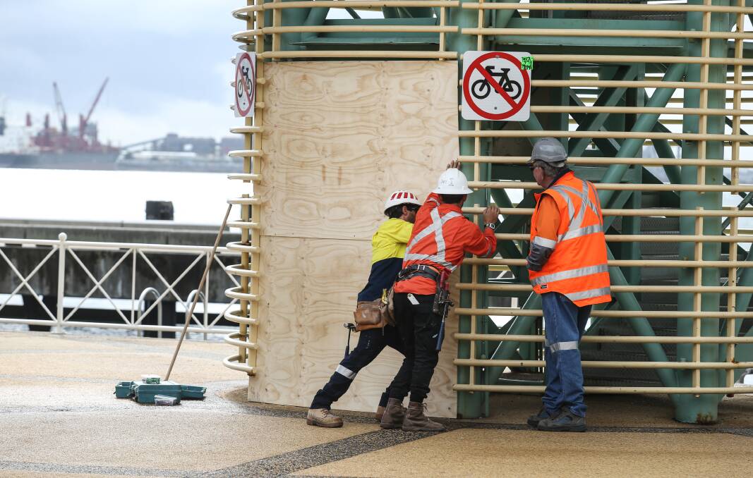 Closing time: A work crew closes the entrance to Queens Wharf tower on Monday. Picture: Marina Neil 