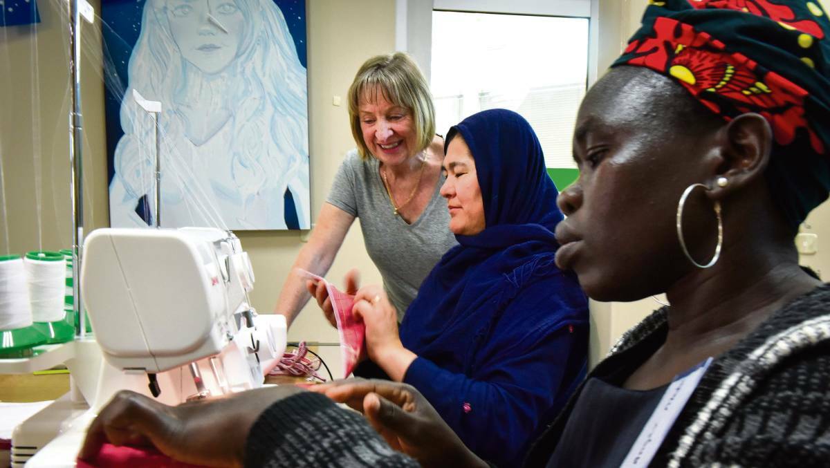 Volunteer sewing teacher Liz Steen with Zakia Sultani and Anger Madut working together making re-usable produce bags at Bendigo's SisterWorks workshop.