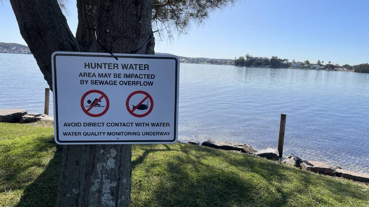File picture of a sign installed when sewerage leaked into Belmont Bay in June last year.