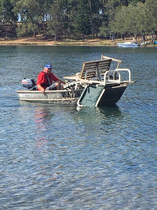 FULLY LOADED: Doug Messenger with a tinny full of plastic furniture and other rubbish extracted from the bush at an abandoned campsite on the Wangi peninsula. Picture: Supplied