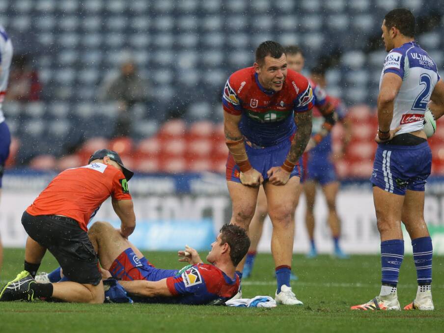 Hamstrung: Knights hooker Andrew McCullough is treated on the ground before being carried off after tearing his hamstring off the bone against the Bulldogs. Picture: Jonathan Carroll.