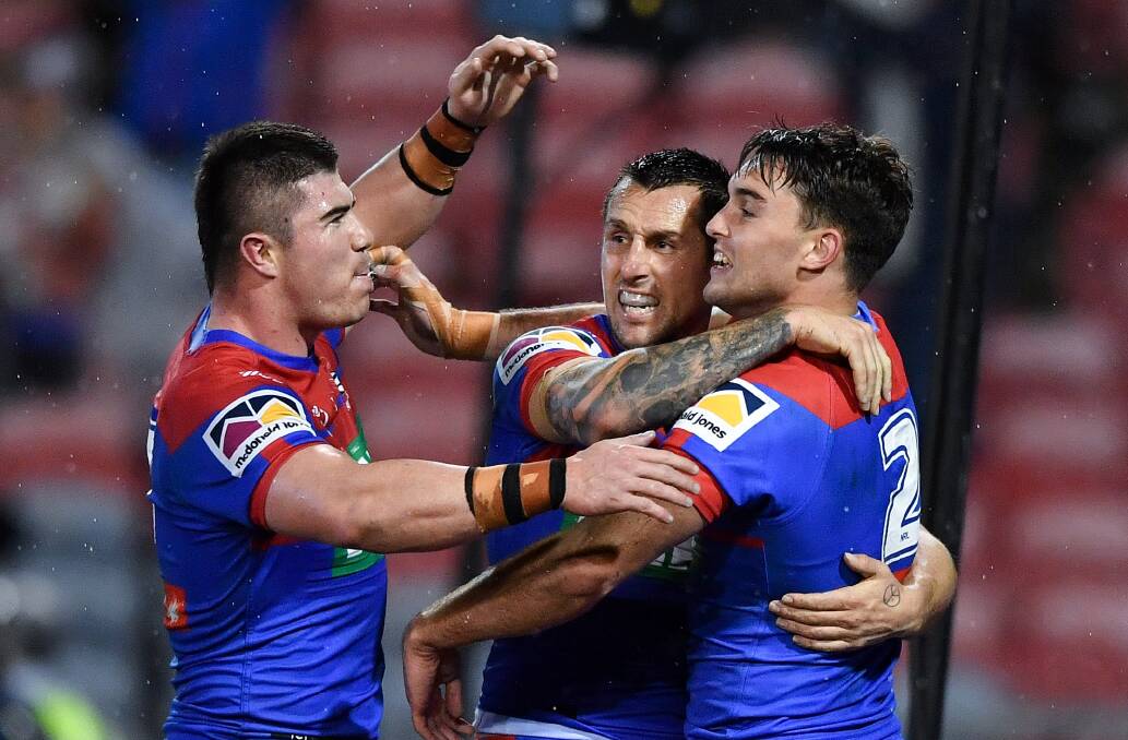 Bradman Best and Mitchell Pearce embrace Tex Hoy before his try is disallowed.