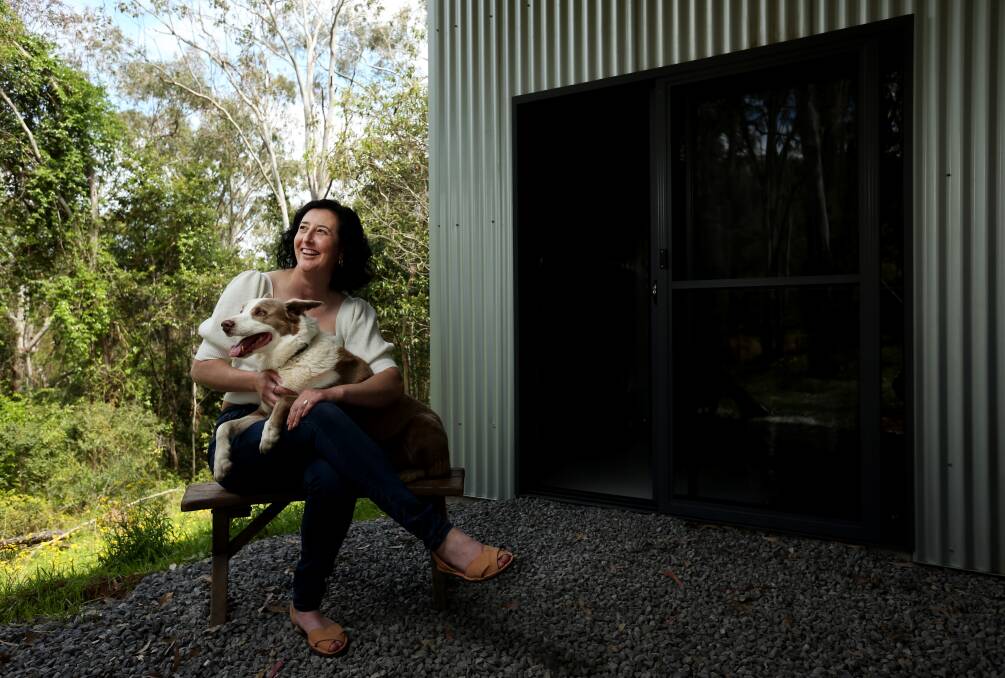 Naomi Rohr, wearing one of her shoe designs, with pooch Gus outside her new work shed. She is currently moving her home office in to the shed space. Picture Simone De Peak 