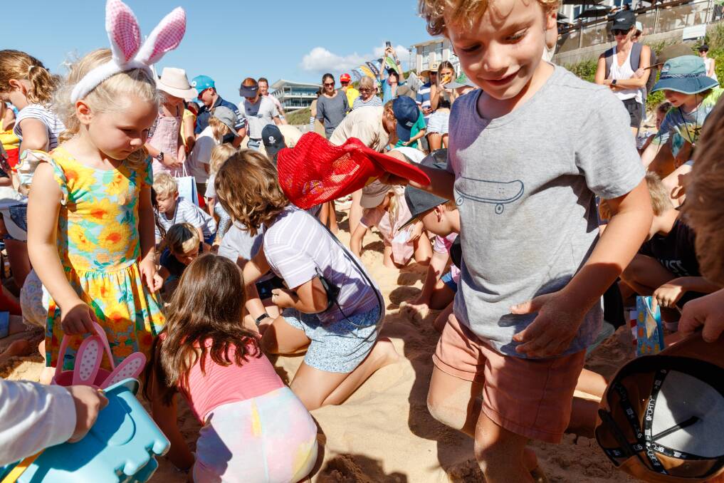 Buried treats: The young and the young at heart rushed to the sand when Merewether Surf Life Saving Club's Easter egg hunt - its first since the pandemic- kicked off on Sunday. Picture: Max Mason Hubers