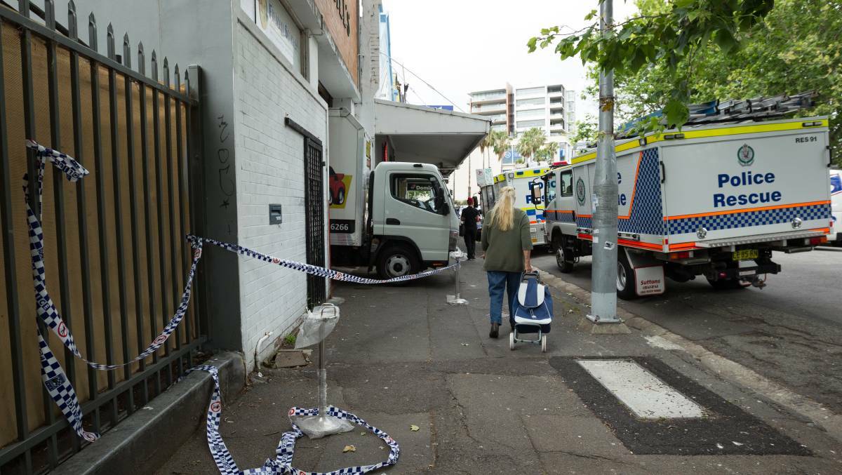 A woman walks past the Steel Street warehouse raided by police. Picture: Max Mason-Hubers