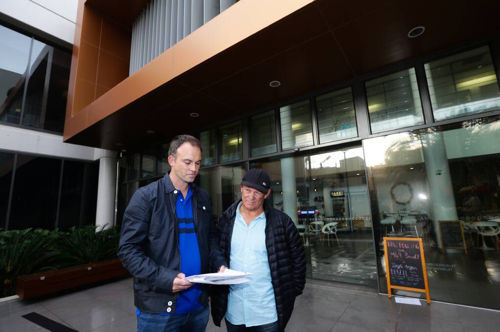 FIGHTING: Williamtown residents Cain Gorfine, left, and Brian Curry serve court documents in Newcastle on Tuesday to appeal the approval of a controversial sand mine on Cabbage Tree Road. Picture: Jonathan Carroll