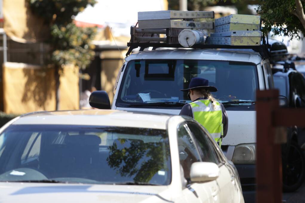 RANGER DANGER: A Newcastle City Council parking officer issues an infringement notice in Wharf Road, one of the region's parking fine hot spots. Picture: Jonathan Carroll