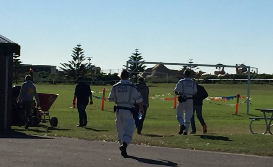 MYSTERY: Police and a camera crew head towards bushland near Corroba Oval, in Stockton, on Tuesday morning investigating the suspected murder of Steven Fenwick. 