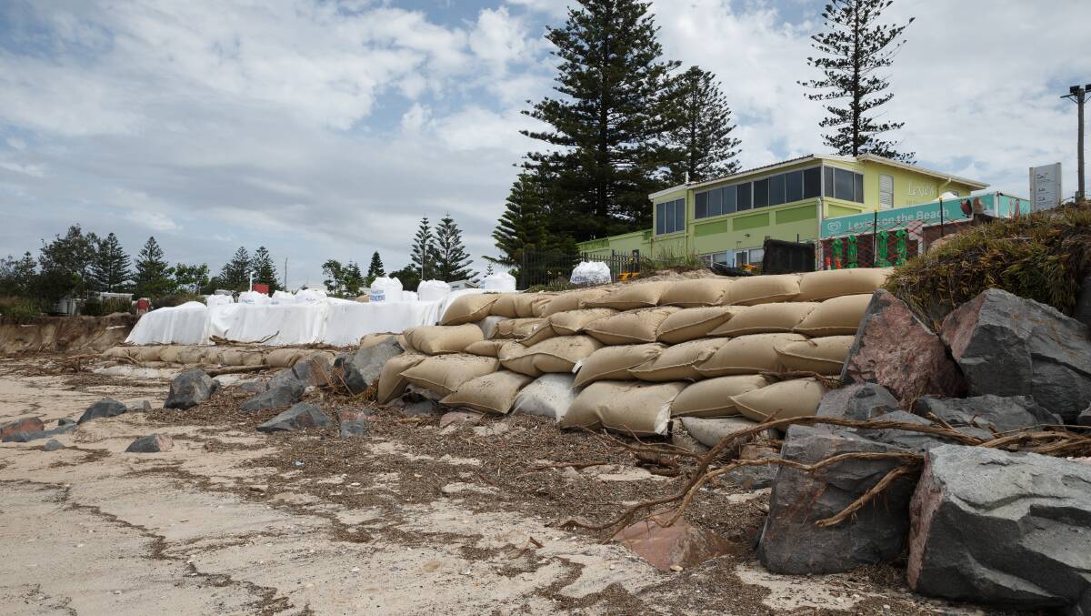 SAD STATE: Emergency sandbagging works at the end of the Stockton Surf Life Saving Club rock wall following severe erosion if February that forced the removal of cabins from the caravan park and temporary closure of Lexie's on the Beach cafe. Picture: Max Mason-Hubers